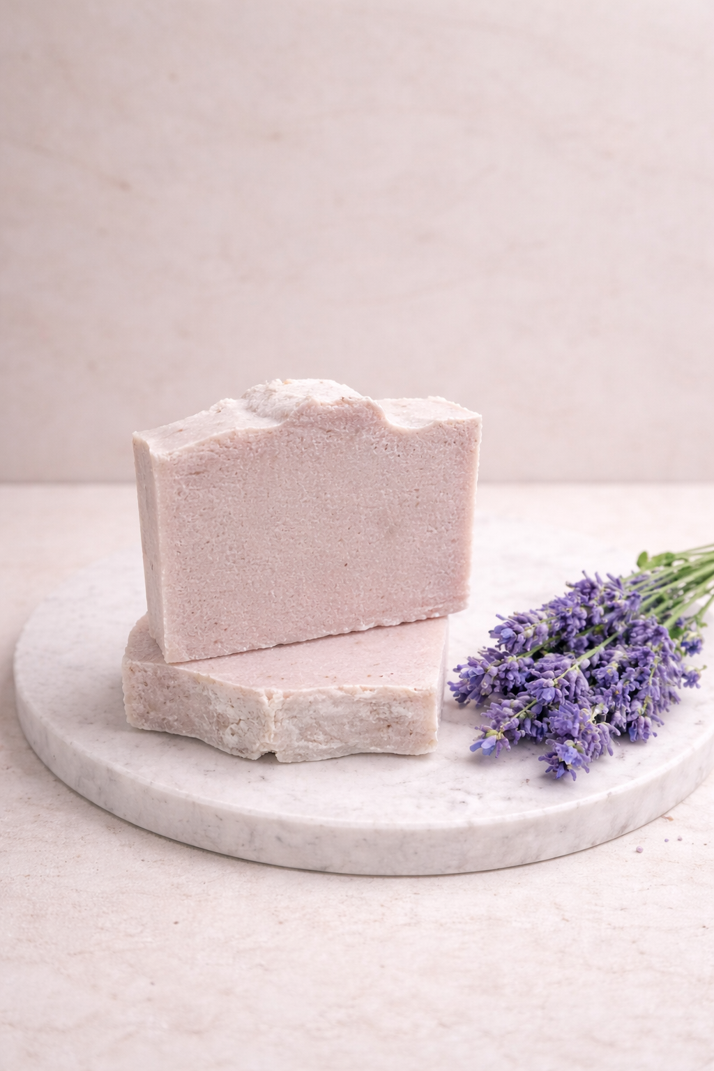 Bar of soap on a marble stand with lavender flowers on a light background