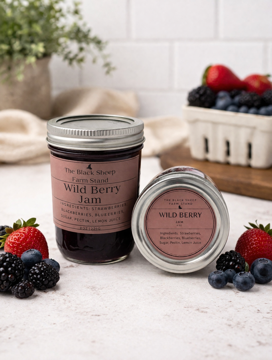 Two jars of Wild Berry Jam from The Black Sheep Farm Stand on a table with fresh berries.