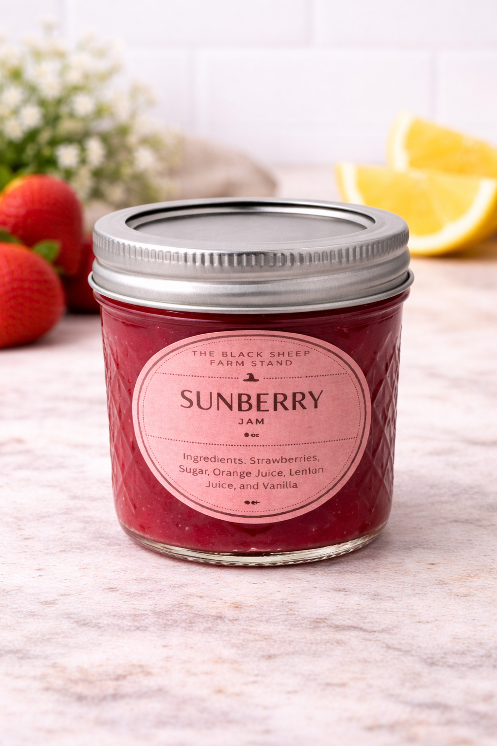 Jar of Sunberry jam with a pink label on a light surface with strawberries and a lemon in the background.