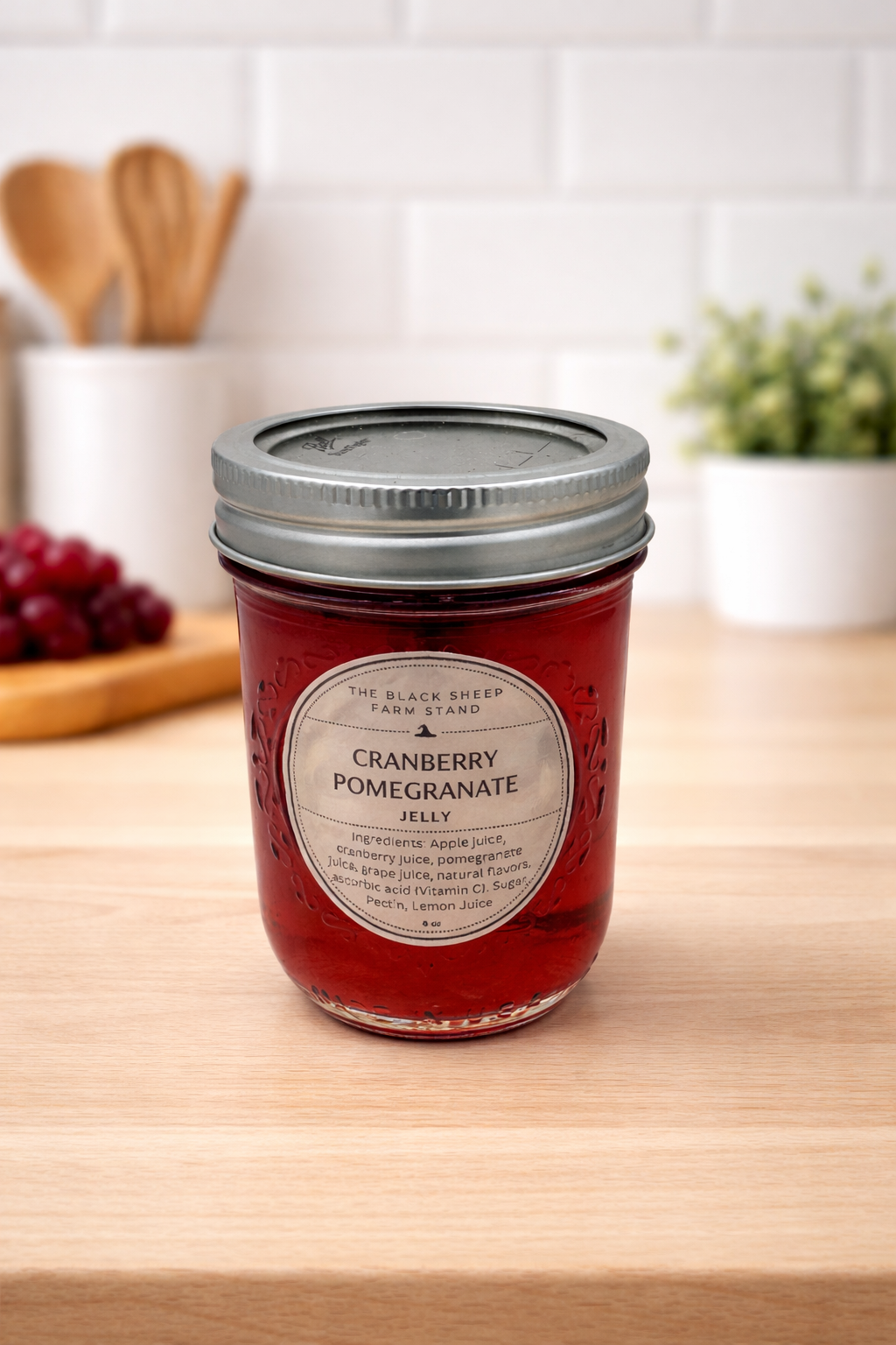 Jar of cranberry pomegranate jelly on a wooden surface with a kitchen background