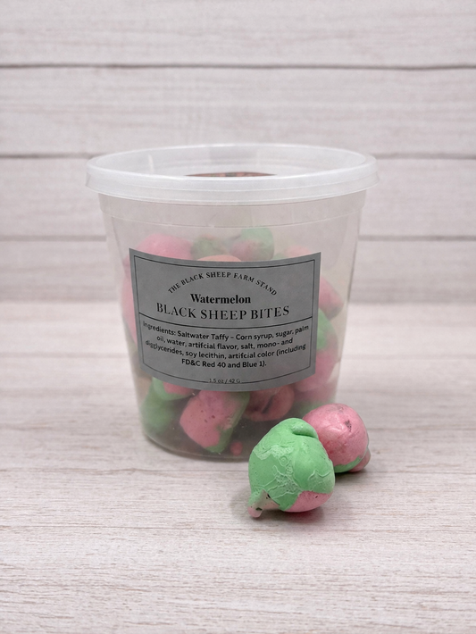 Clear container with pink and green treats labeled 'Black Sheep Bites' on a light wooden surface.