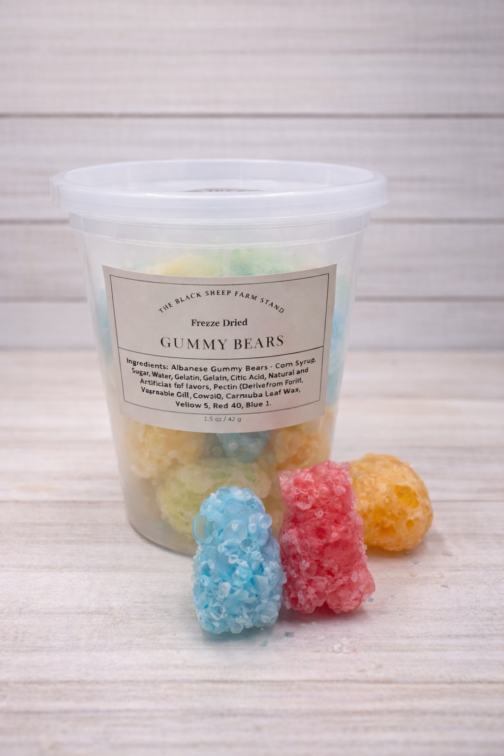 Clear container of freeze-dried gummy bears with a label on a light wooden surface.