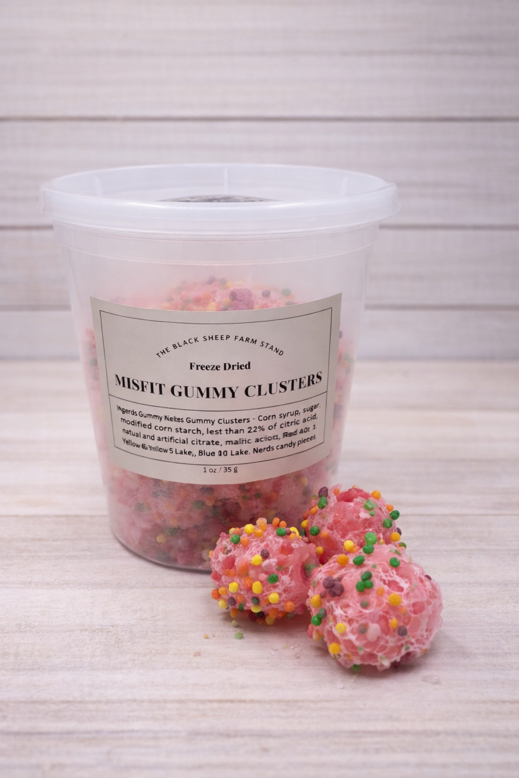 Container of misfit gummy clusters with a label on a wooden surface