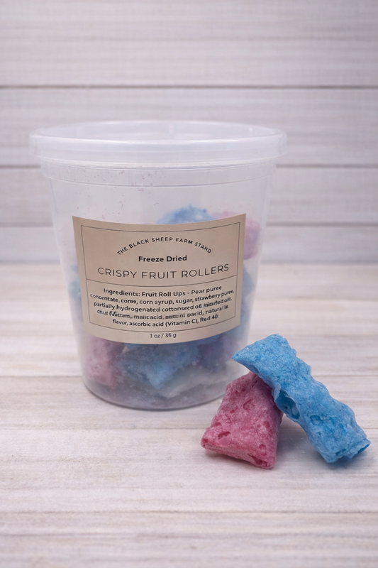 Container of freeze-dried crispy fruit rollers with two rolls on a white background