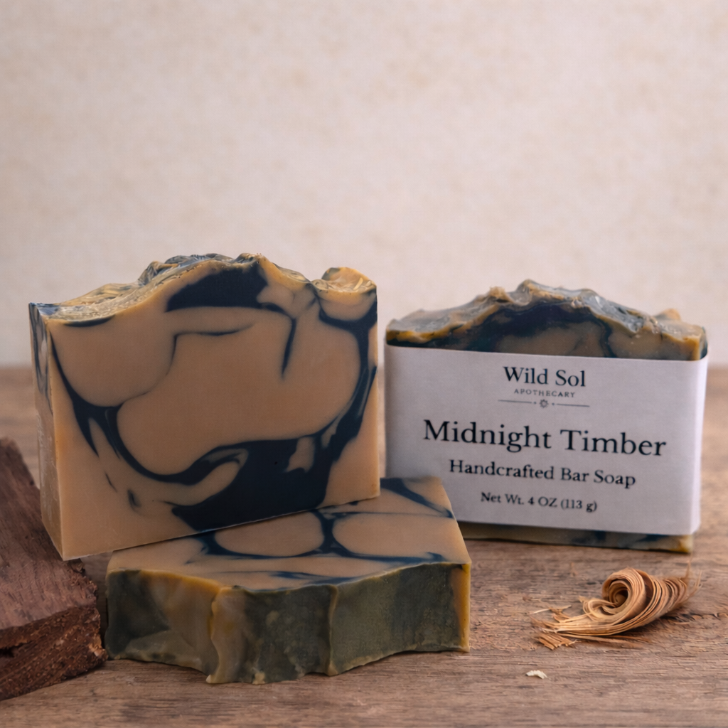 Handcrafted bar soap with marbled design and packaging labeled 'Wild Sol Midnight Timber' on a wooden surface.